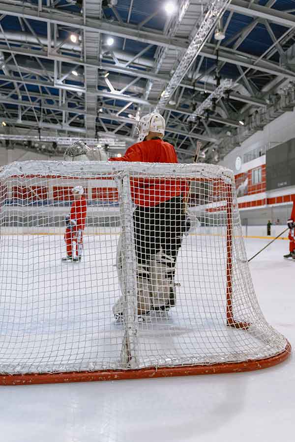 cage hockey sur glace sportif habillé en rouge sur patinoire